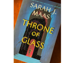 Image of a book cover, Throne of Glass by Sarah J Maas. Gems have been added to the cover to decorate it.